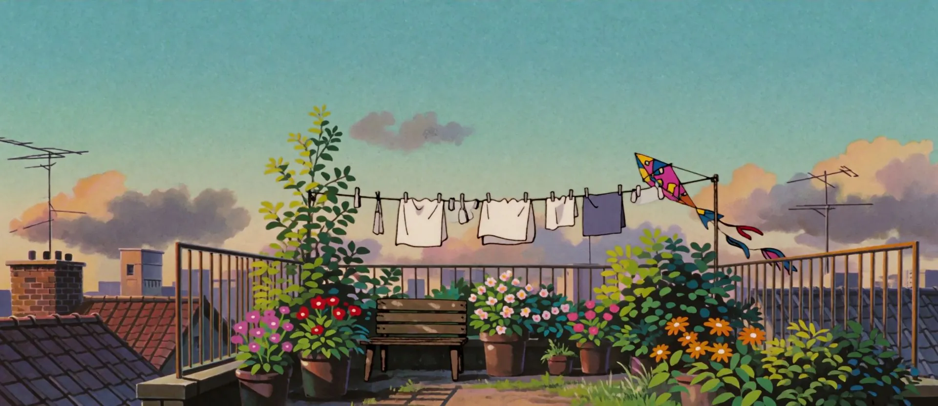 A painted rooftop garden at sunset, washing on a line and a kite caught in it